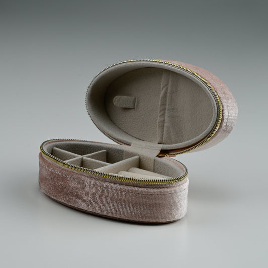 Open blush oval velvet jewellery box showing compartments and lid pocket