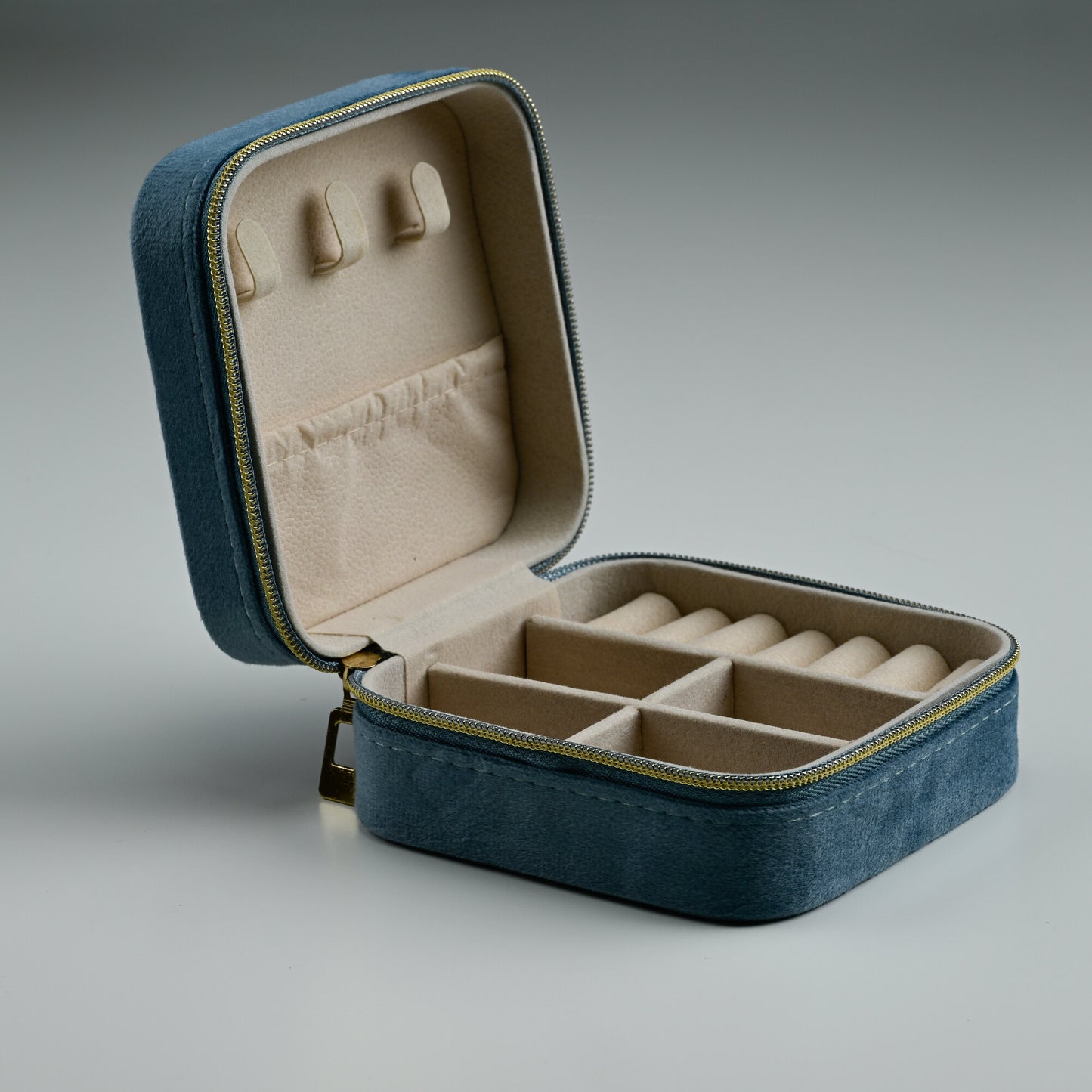 Open dusty blue velvet travel jewellery box with ring rolls and padded lid