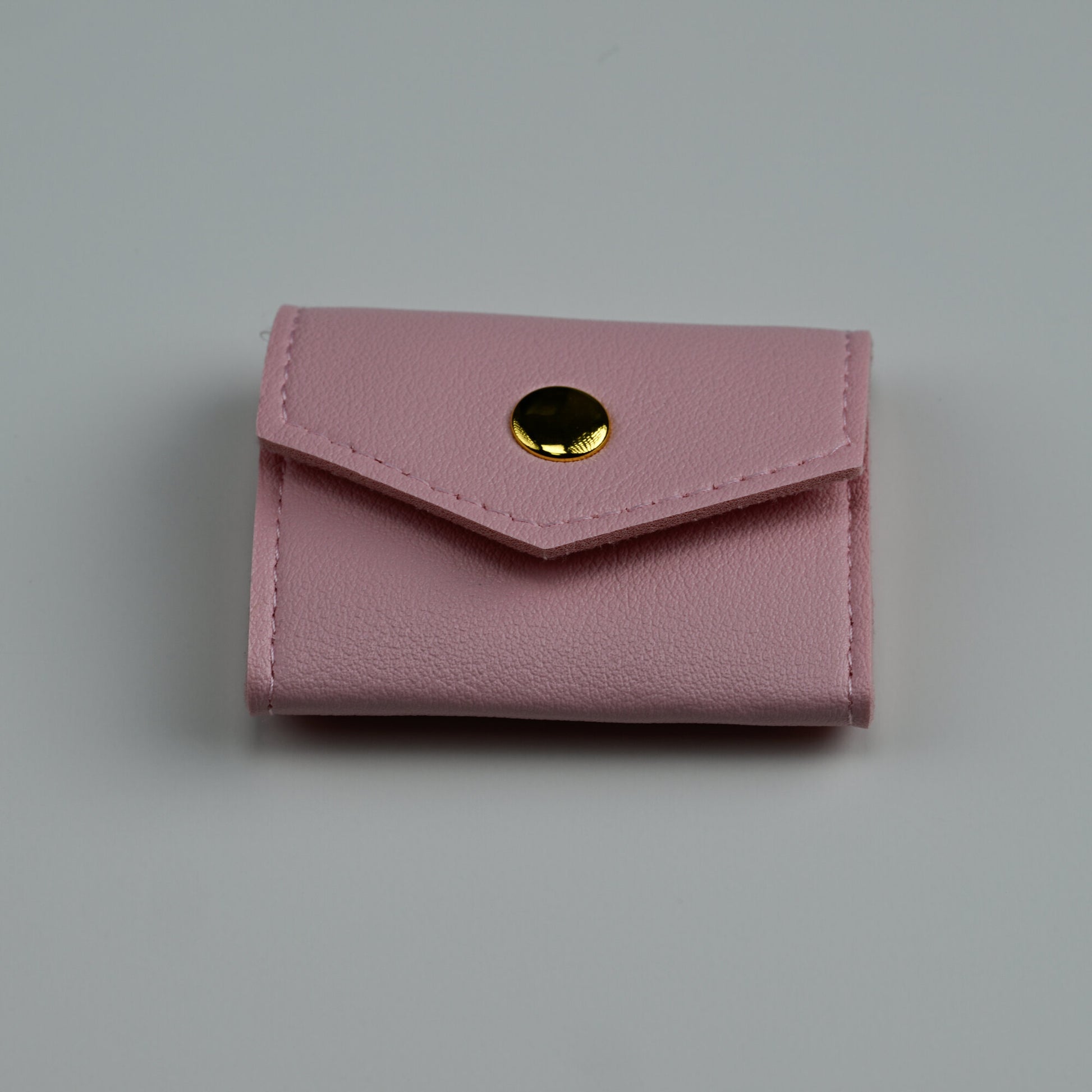 Pink faux-leather envelope jewellery pouch with gold snap, closed