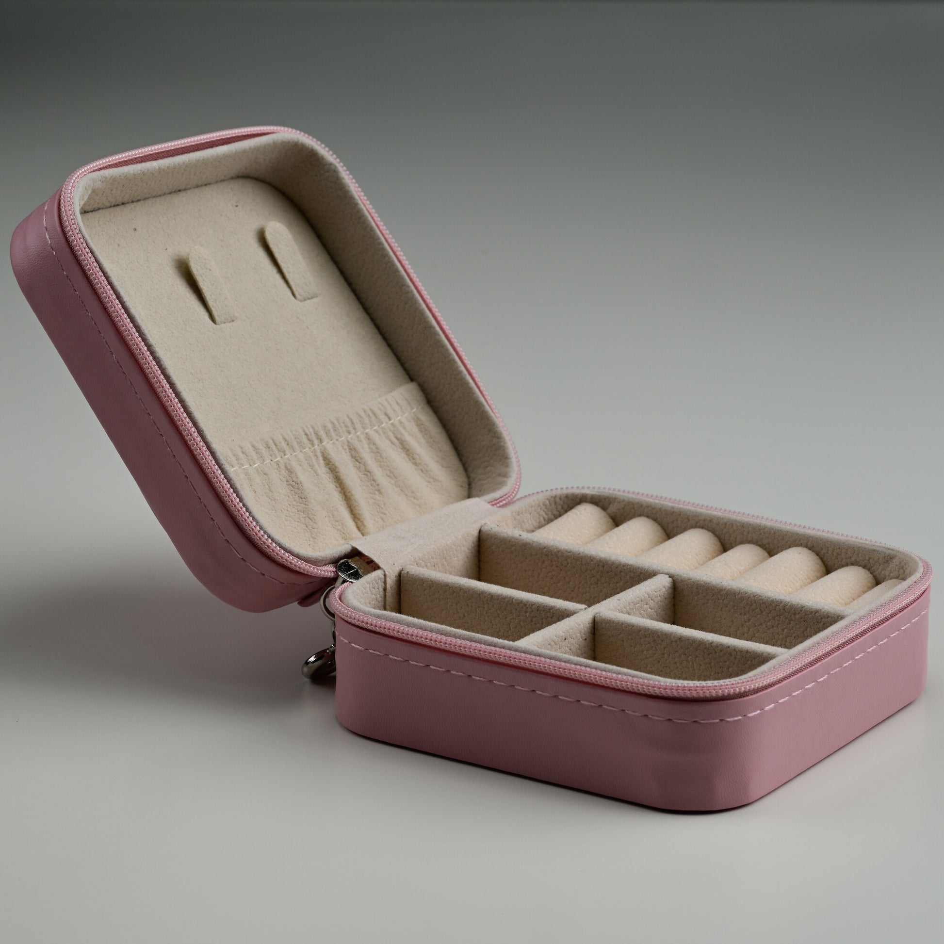 Open pink leather travel jewellery box showing ring rolls and compartments