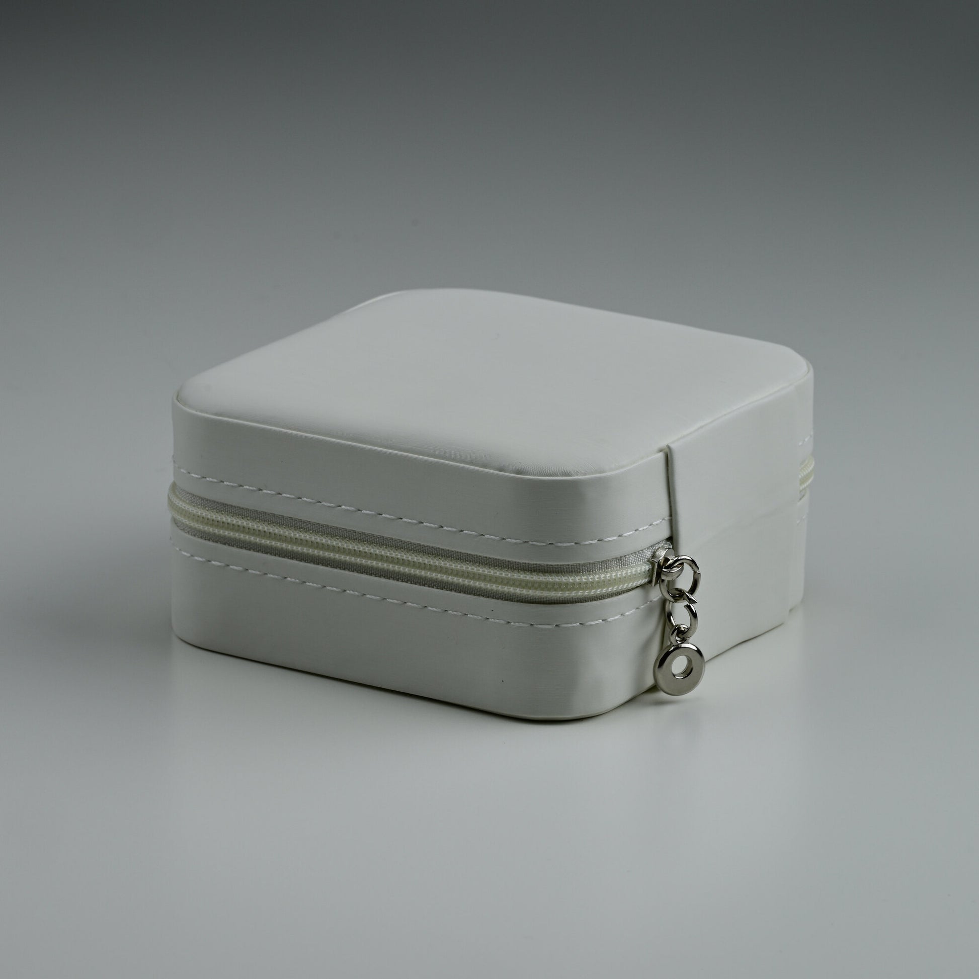 White faux-leather travel jewellery box with silver zip, closed