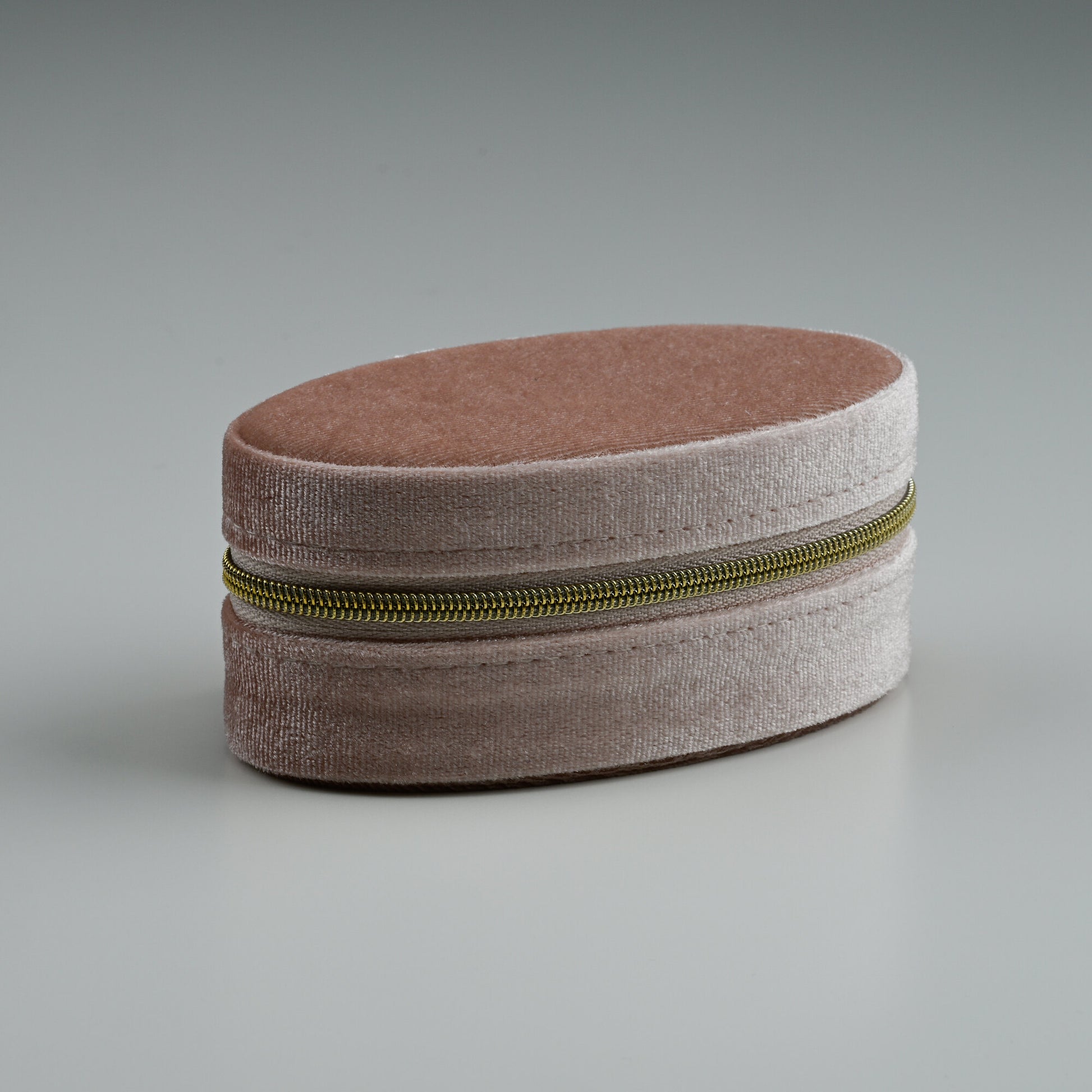 Blush oval velvet jewellery box with gold zip, closed
