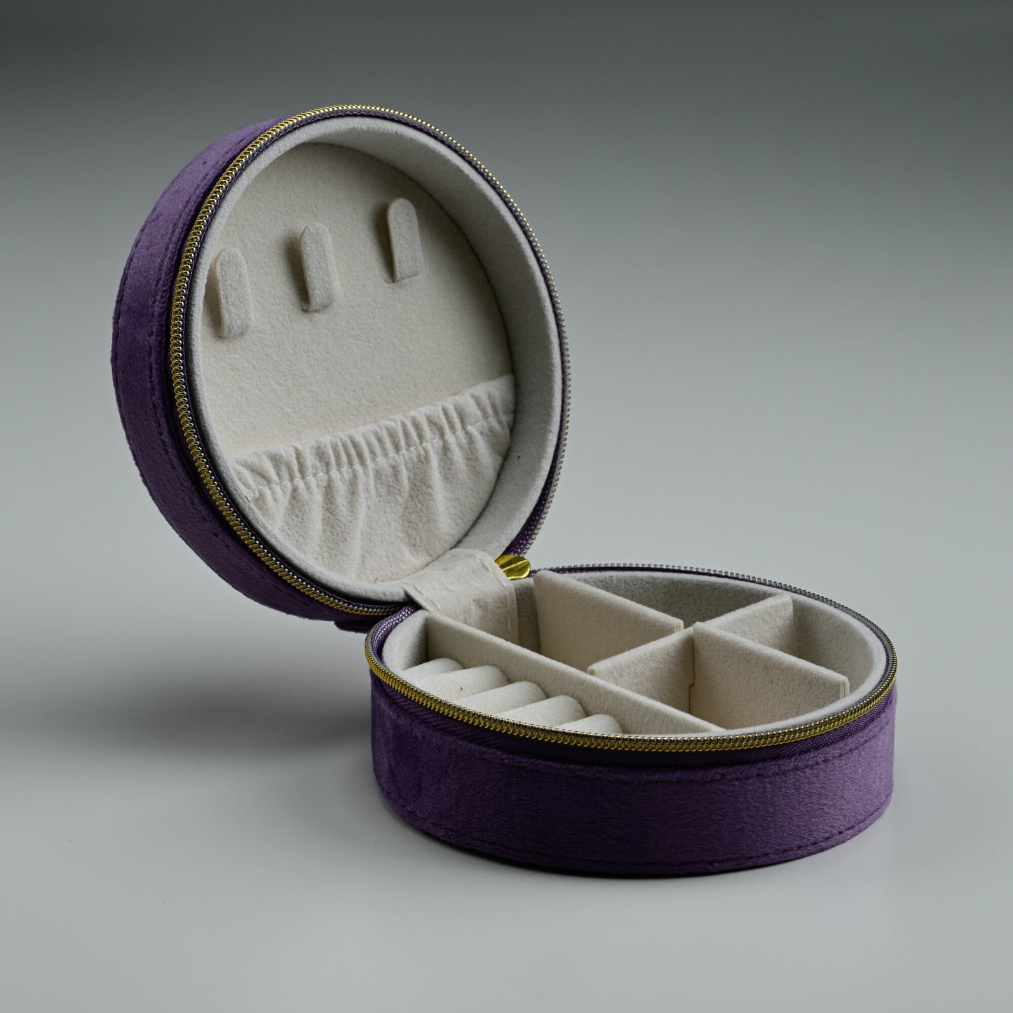 Open purple round velvet jewellery box with divided compartments