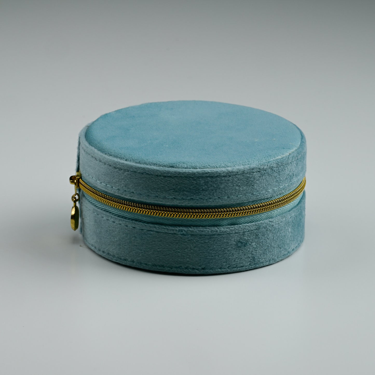 Teal round velvet jewellery box with gold zip, closed