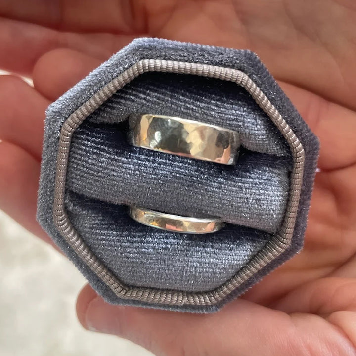 Phineas — silver wedding bands in a velvet ring box, held in a hand
